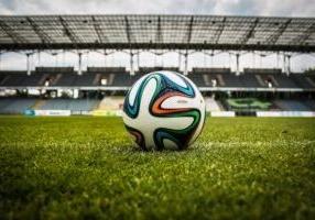 A soccer ball sitting on an empty field within a stadium.